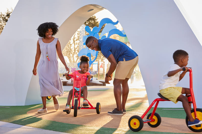 Niños montando triciclos en el parque temático de Peppa Pig