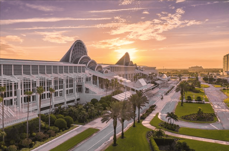 Modern architecture of the Orange County Convention Center along International Drive, framed by palm trees at golden hour