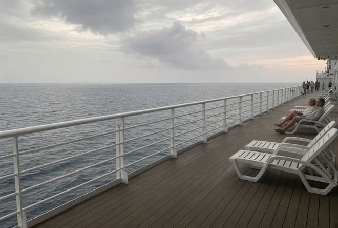 Cubierta de un crucero con tumbonas pasajeros y mar abierto al frente